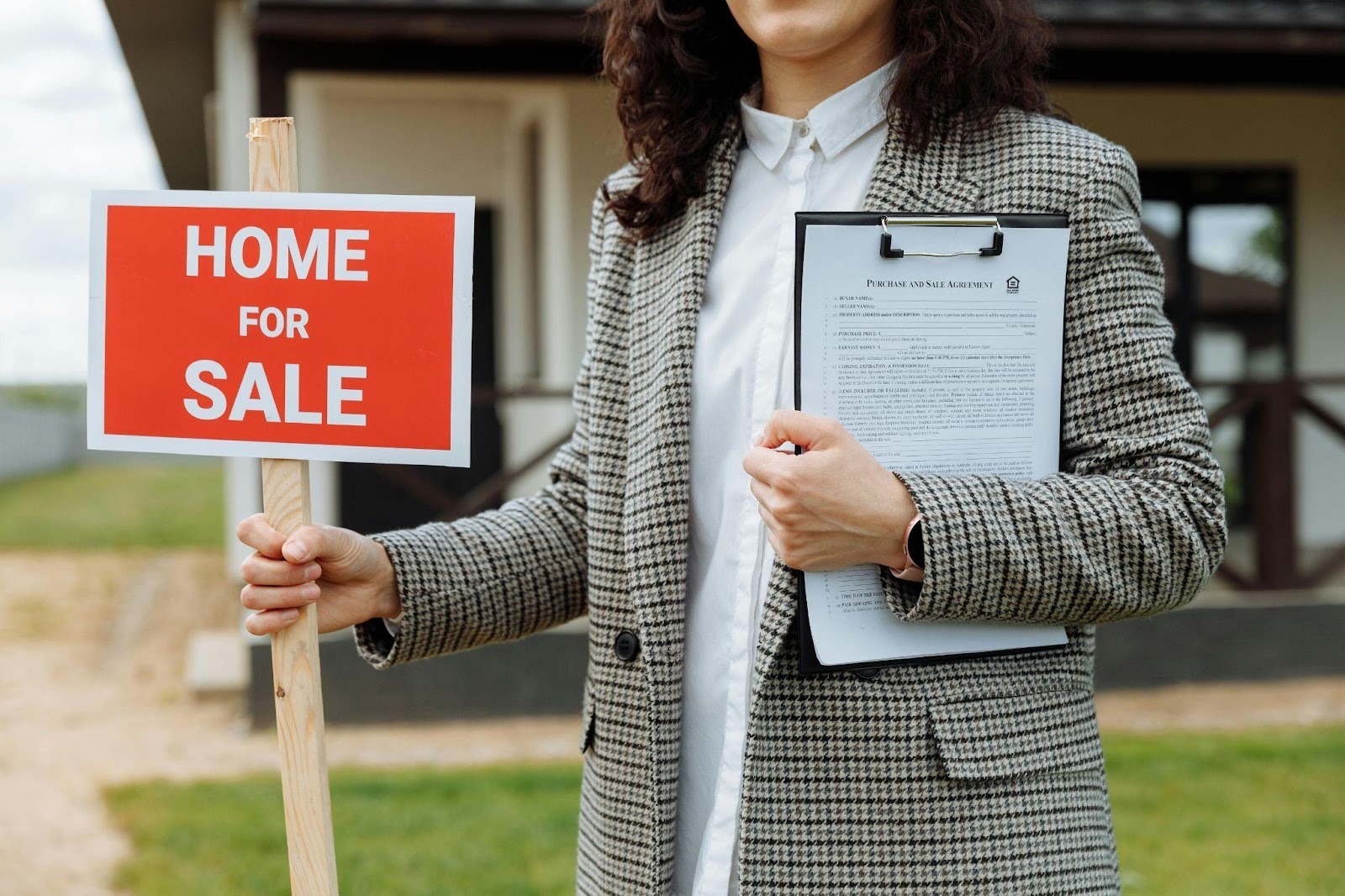 person holding home for sale sign