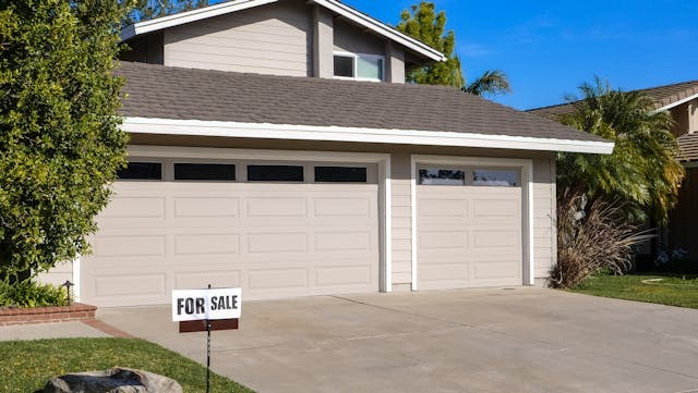 exterior of home in the summer with a for sale sign