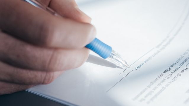 a person signing the bottom of a form