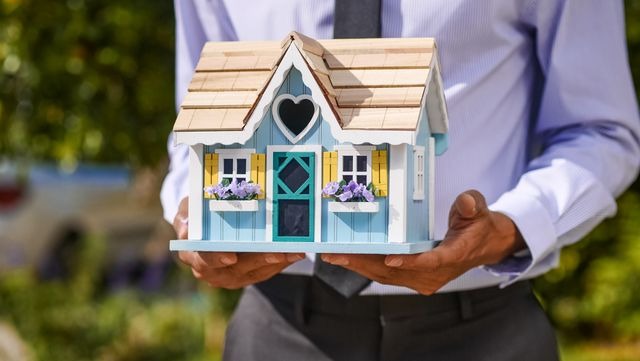 a person holding a small house model